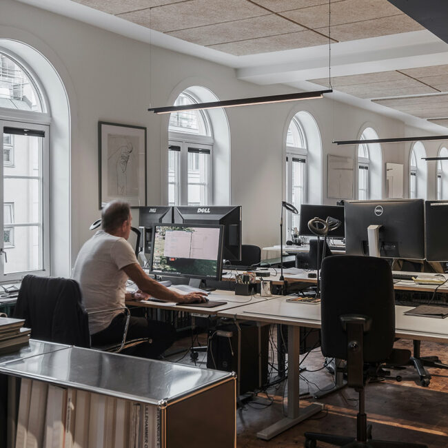 Mann som jobber ved en arbeidsstasjon inne hos Fabel Arkitekter.