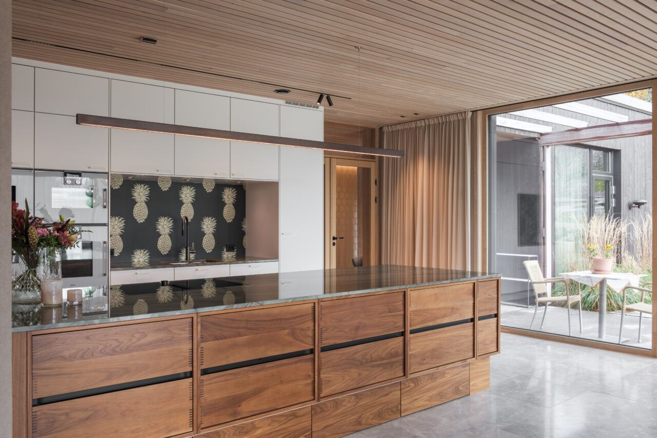 Kjøkken med spotter i taket og led pendel over kjøkkenøy.