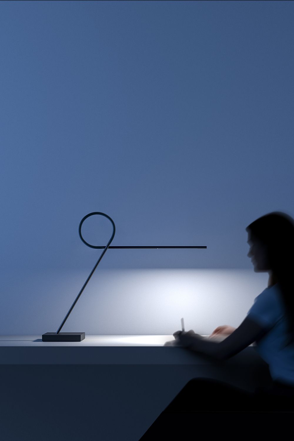 Ribbon bordlampe ved siden av en mann som leser.