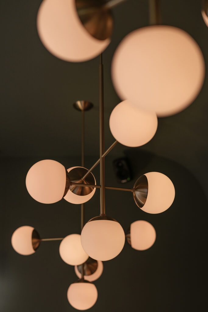 Messingfarget pendellampe med hvit glasskuppler som henger fra taket.