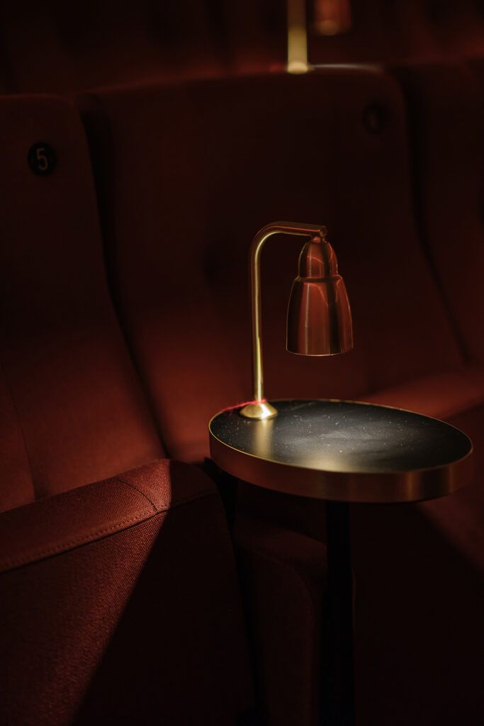 Messing bordlampe på et rundt bord ved en sitteplass.