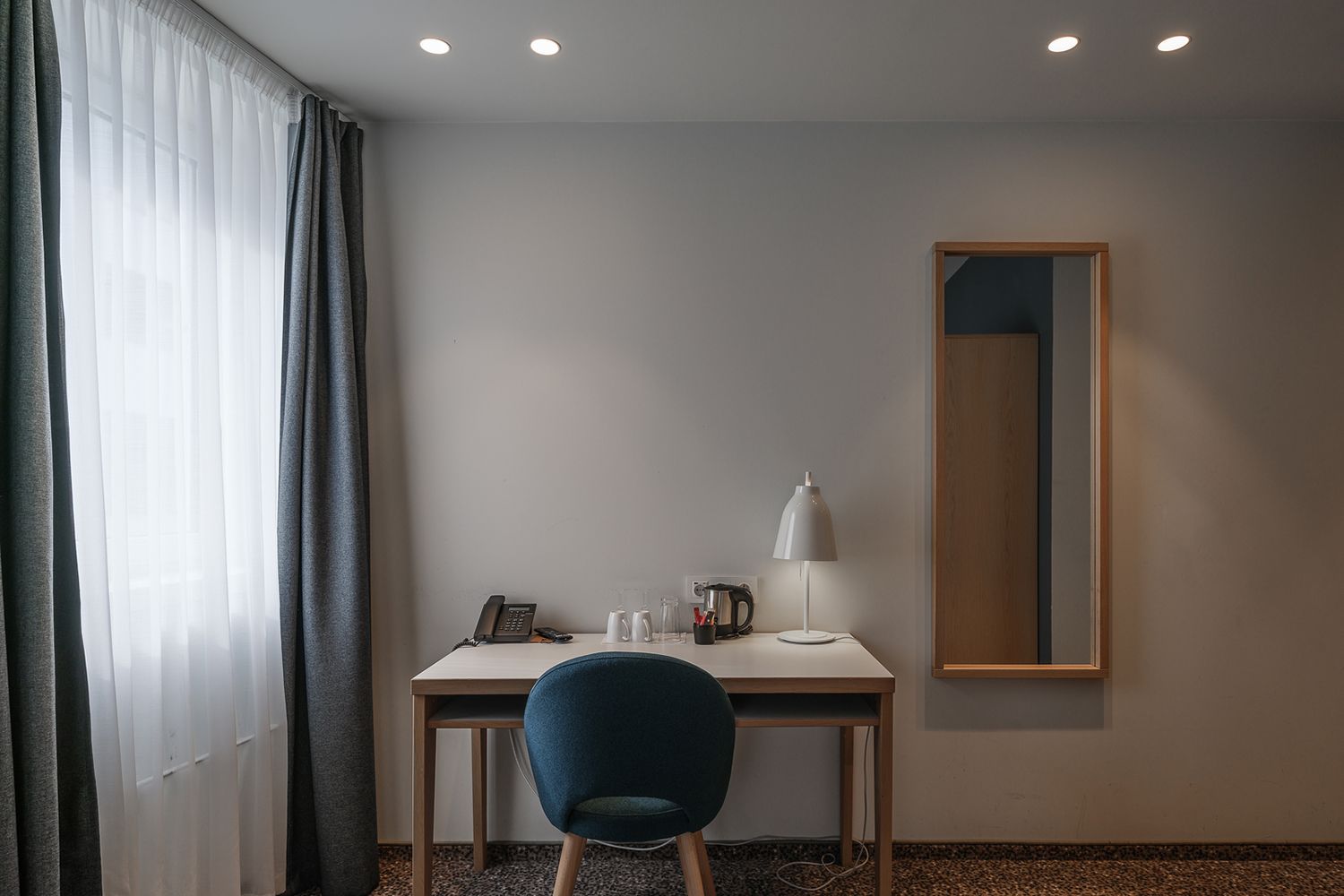 Downlight i et tak og en bordlampe på et skrivebord i et værelse i Hotel Noreg.