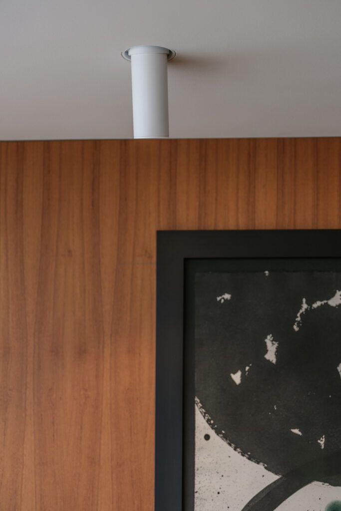 Nærbilde av innfelt hvit spot i et hvitt tak som belyser et bilde.