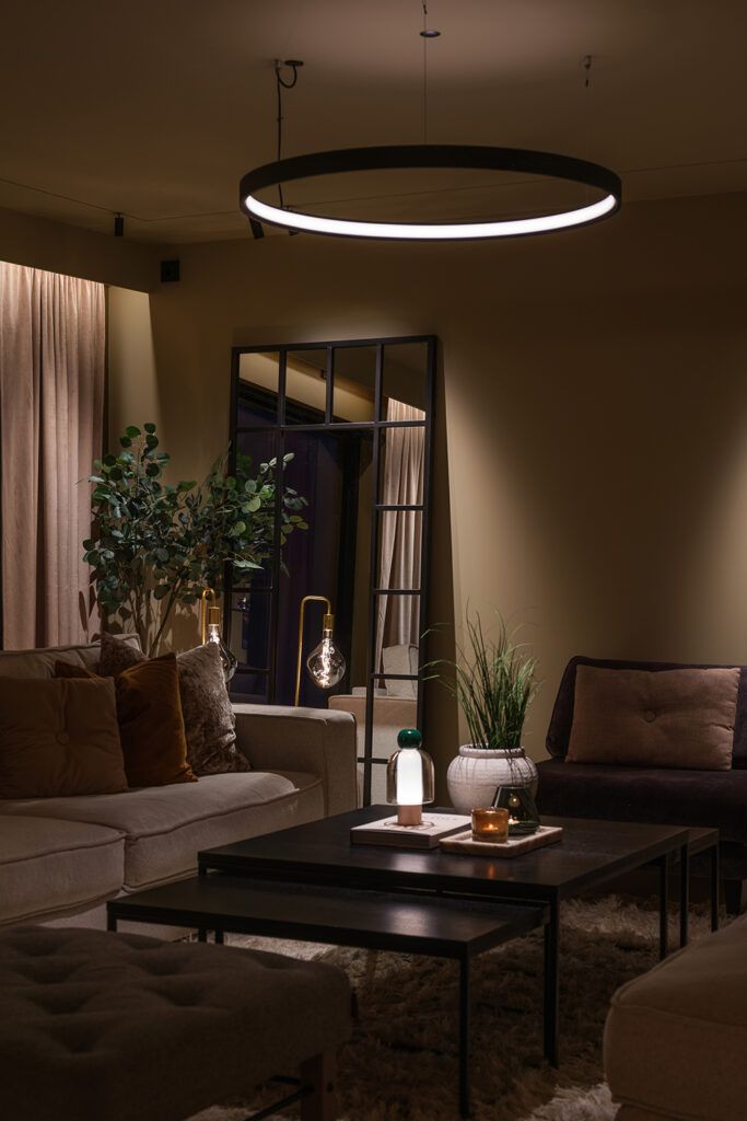 Rund pendel over spisebord og slepelys langs gardiner.