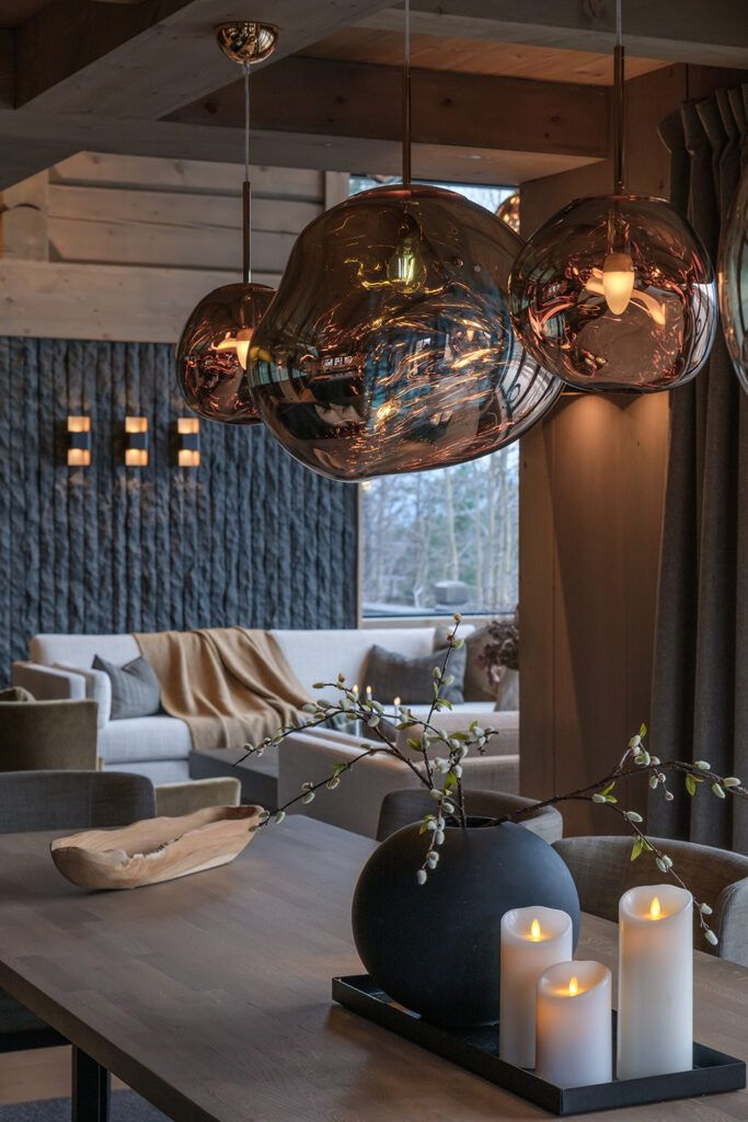 Runde amberfarget glasskupler over et spisebord i Orretundet hytte på Strandafjellet.