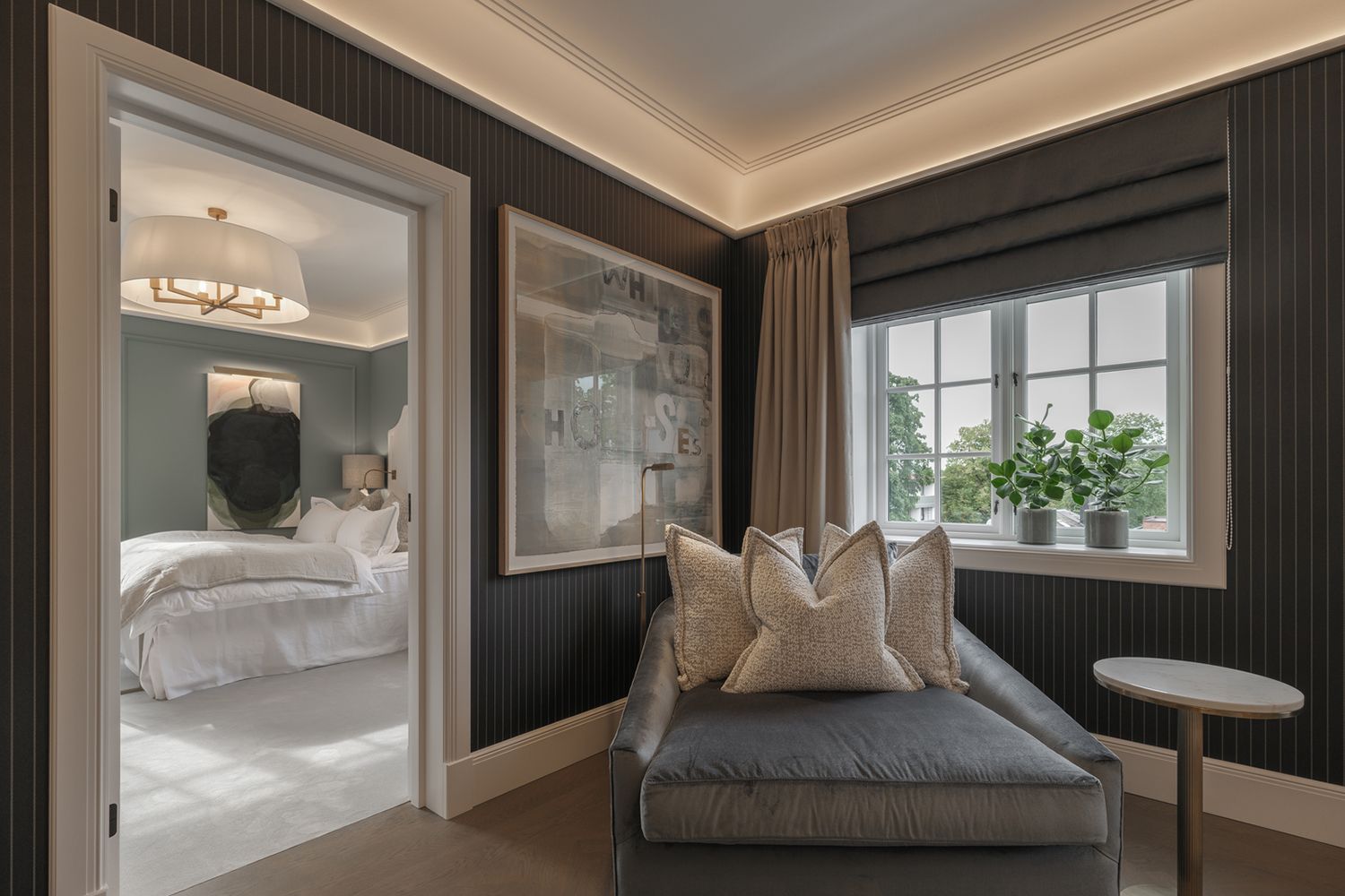 Hjørne i et stue med slepelys mot taket og en godstol i hjørnet med leselampe på gulvet.