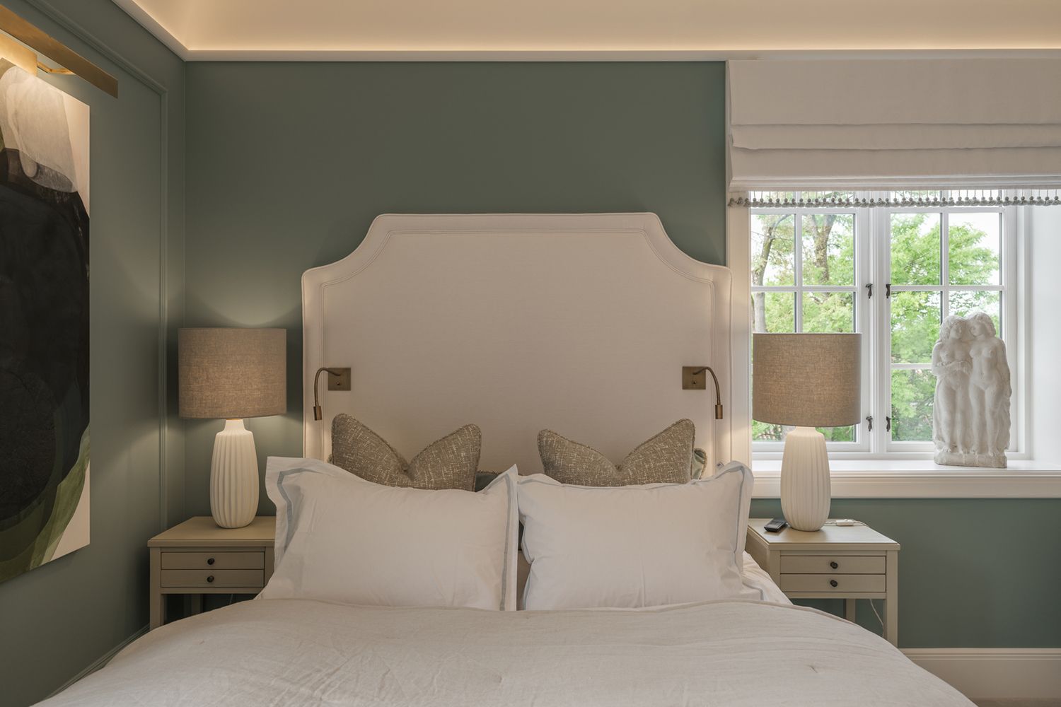 Soversom med grønn vegger, slepelys i taket for indirekte lys og bordlamper på hver sin side av sengen.