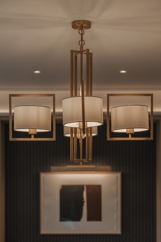 Gullfarget pendel med fire hvite skjermer og dorwnlight i taket.