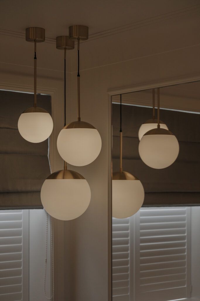 Tre pendler med opale glasskupler i taket i et hjørne.