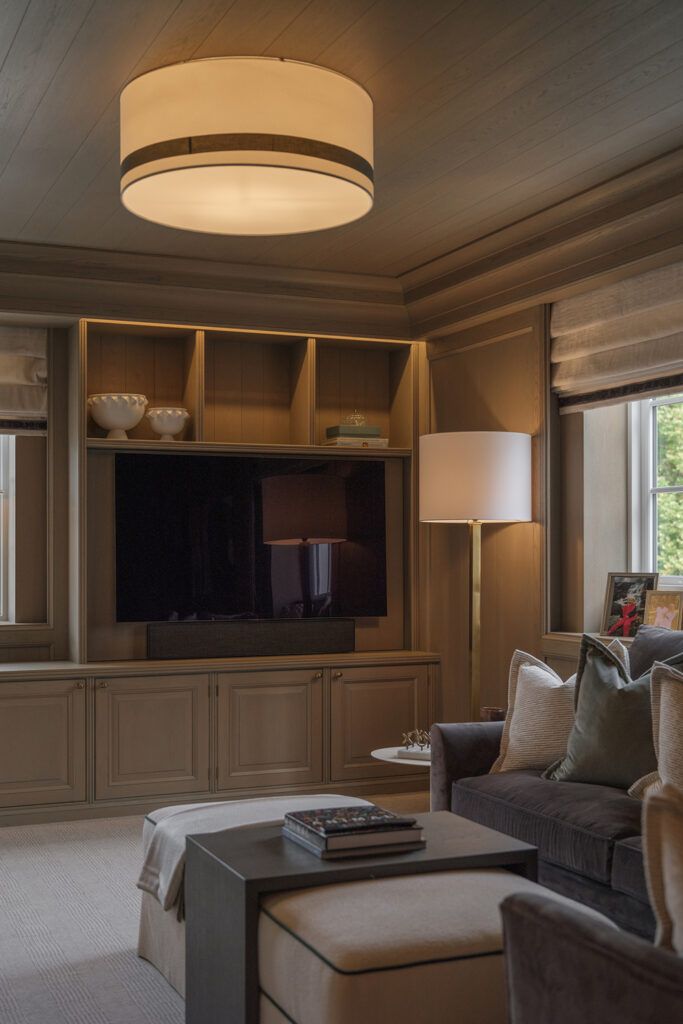 Reol med belysning, og rund skjerm i taket og en gulvlampe på gulvet med lys skjerm.