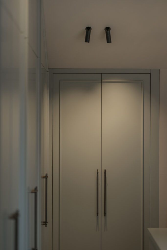 To sorte spotter i et tak som belyser grønne garderobeskap.