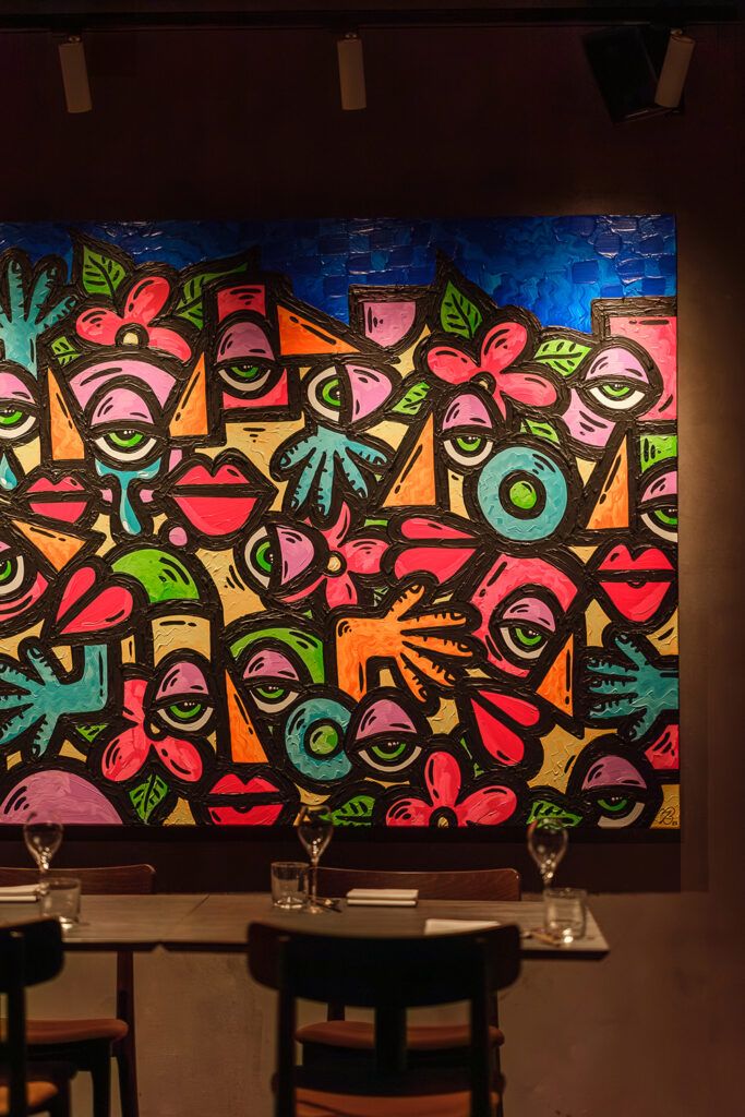 Fargerikt bilde på vegg i Kombo Trondheim, belyst med spotter i taket.