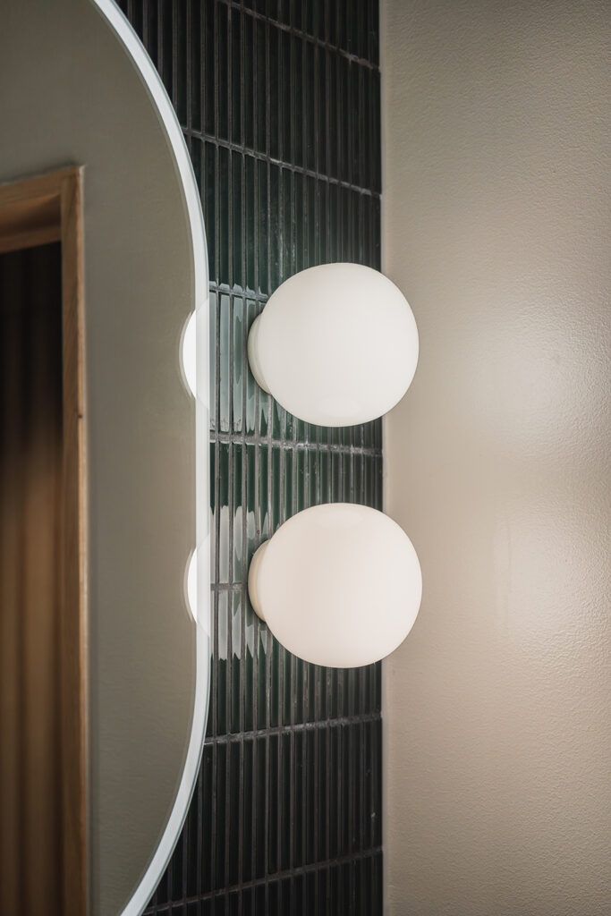 To runde opalhvite vegglamper ved siden av et speil.