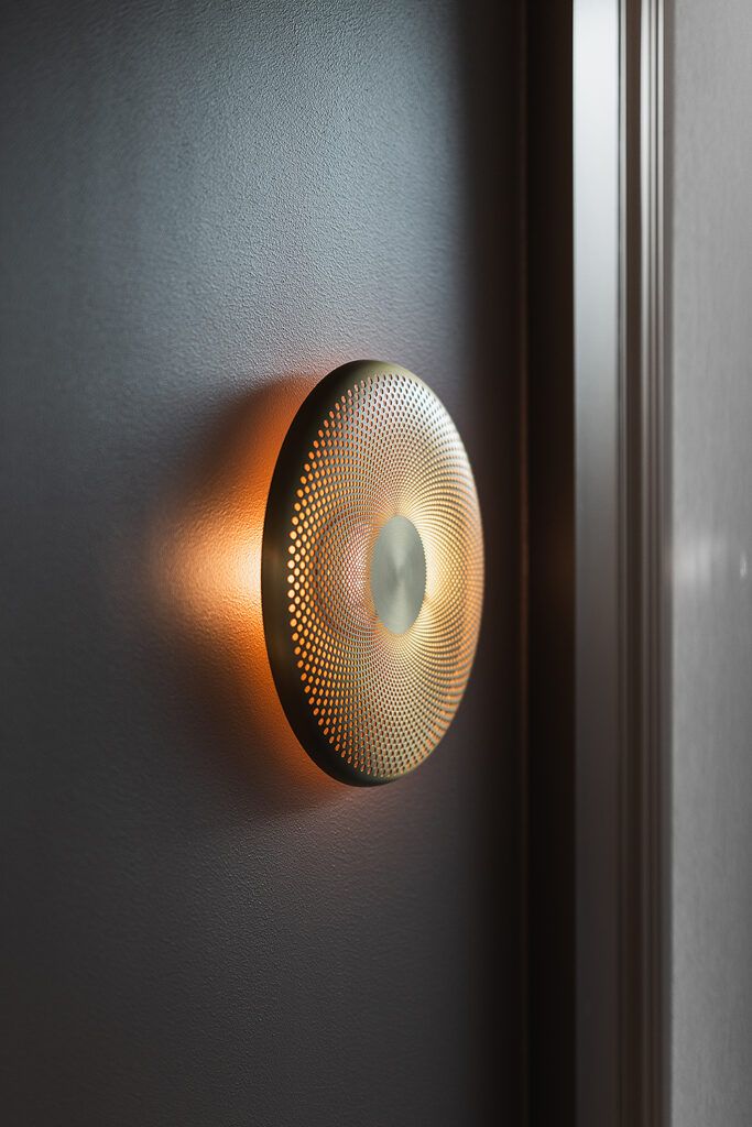 Rund dekorativ vegglampe på en sort vegg.