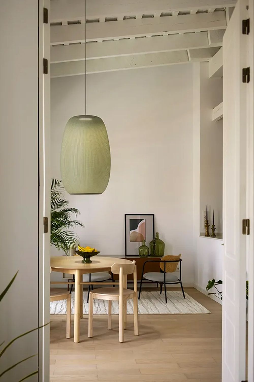 Lys grønn Closer pendel fra Vibia henger over et bord.