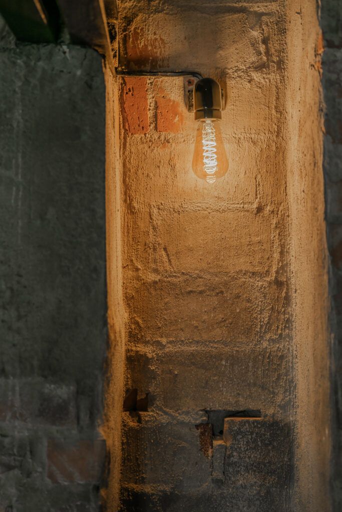 Dekorativ lyspære i en sort sokkel mot en mur.