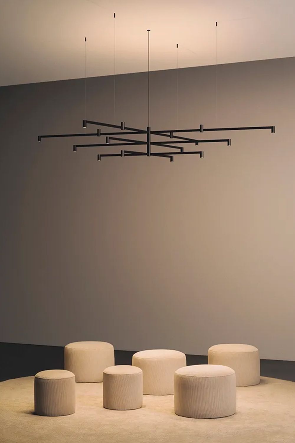 Nexum pendel fra Vibia over noen puffer som står på et gulv.