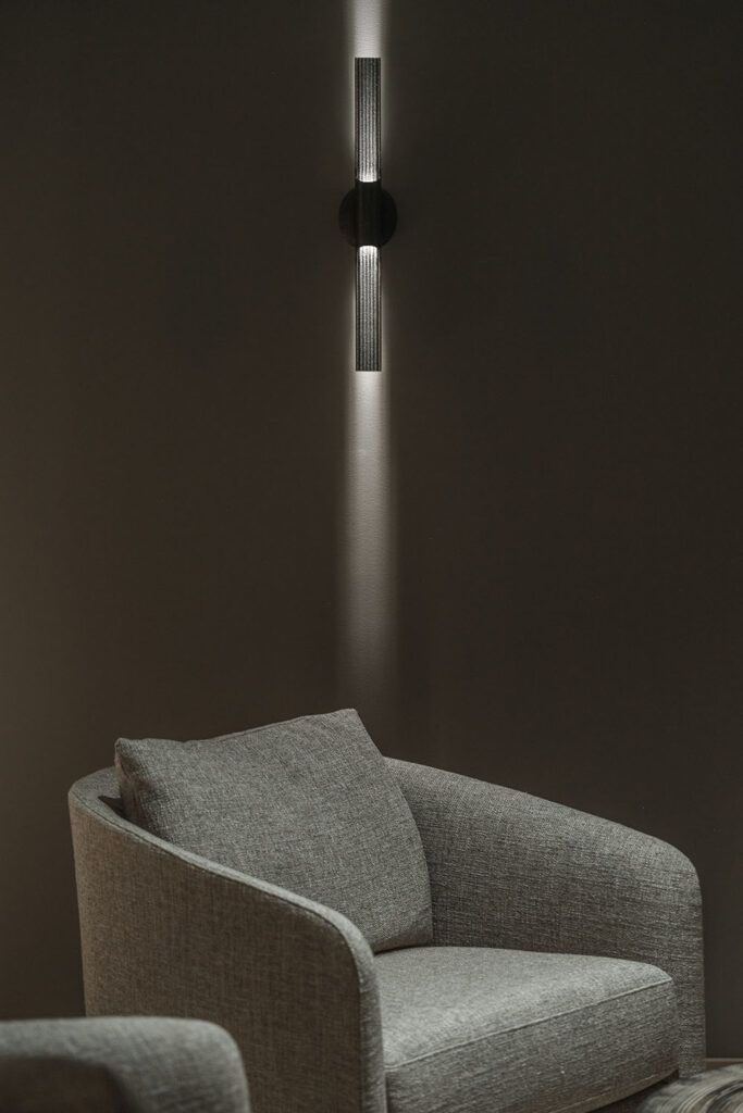 Dekorativ lampe på vegg over en stol.