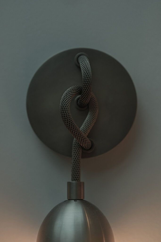 Nærbilde detaljer på en vegglampe viser en knute i metall.