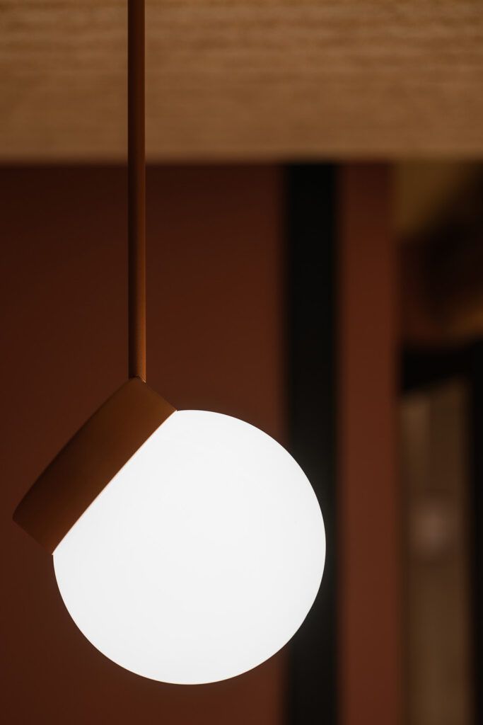 Lampe med hvit rund kuppel som henger i et tak.