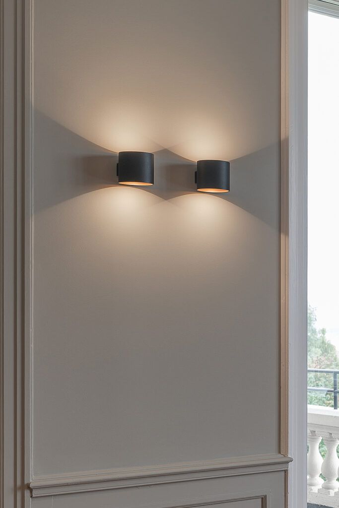 Nærbilde av to vegglamper på en hvit vegg.